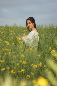 Young woman with yellow flowers on field