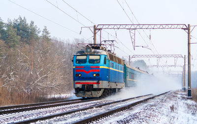 Train on railroad tracks against sky during winter