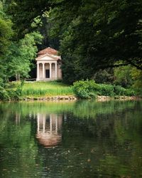 Built structure by lake against trees and plants