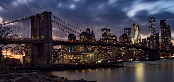 Illuminated bridge over river in city at night