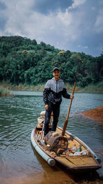 Man in boat on lake against sky