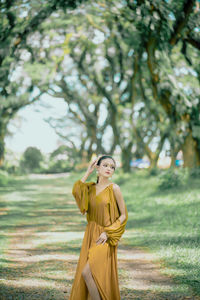 Young woman standing against trees