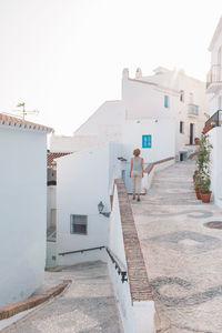 Woman standing by staircase in city against sky