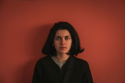 Portrait of beautiful young woman against red background