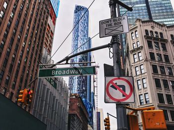 Low angle view of road signs against buildings in city