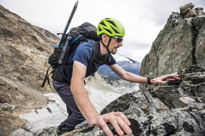 Side view of backpacker climbing over rocky terrain.