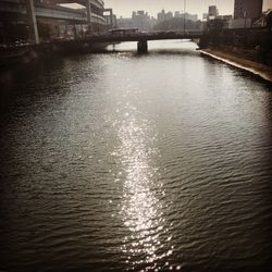 Bridge over river in city against sky