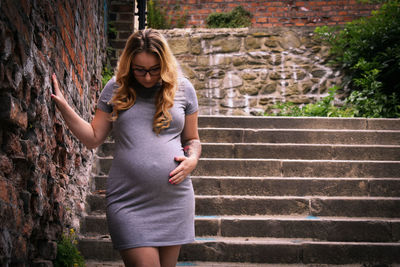 Pregnant woman on staircase by stone wall