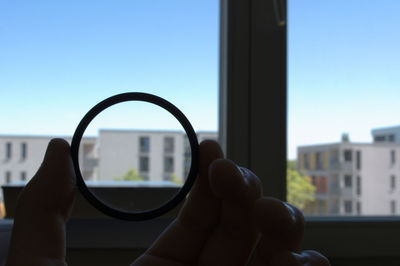 Close-up of hand against window against clear sky