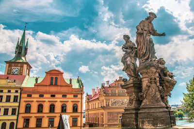 Low angle view of statues on building against cloudy sky