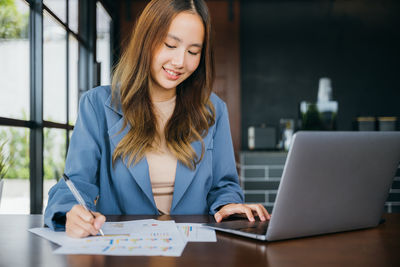 Portrait of young woman using laptop at table