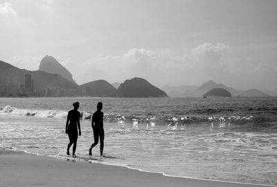 Rear view of people on beach against sky