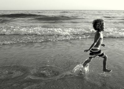 Full length of shirtless boy on beach