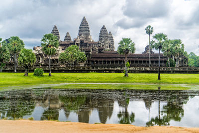 Panoramic view of temple by lake and buildings against sky