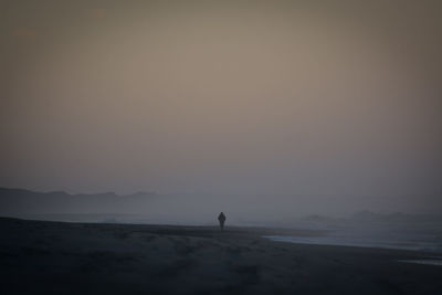 Silhouette man on beach against sky during sunset