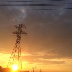 Silhouette of electricity pylon at sunset