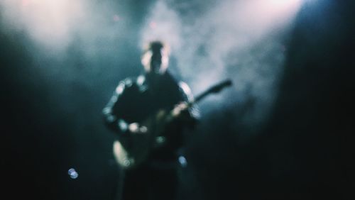 Person holding guitar at night