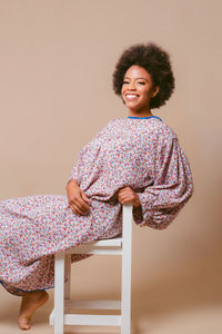 Portrait of smiling young woman standing against white background