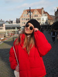 Beautiful woman wearing sunglasses standing against city in background