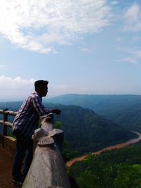 Man climbing on mountain against sky