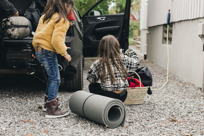 Sisters loading luggage in electric car trunk while going for picnic