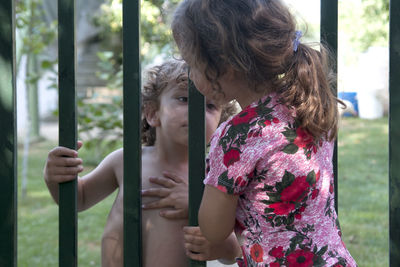 Siblings standing by gate