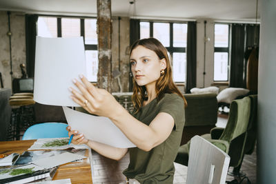 Young female entrepreneur comparing photographs at table in studio