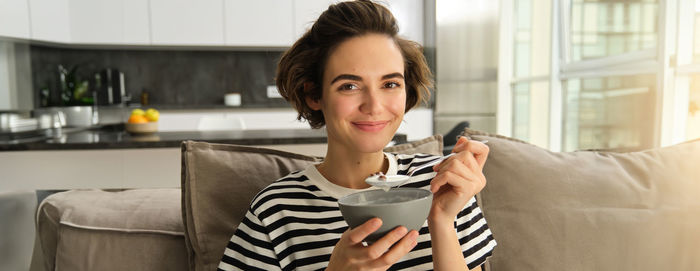 Young woman using mobile phone while sitting at home