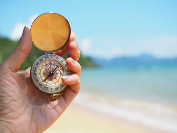 Close-up of woman holding navigational compass at beach
