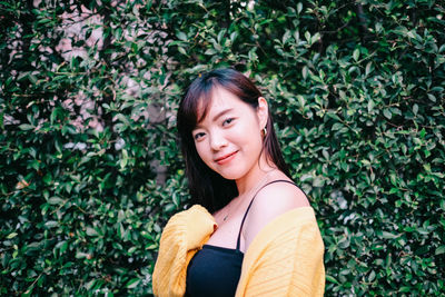 Portrait of smiling woman standing against plants