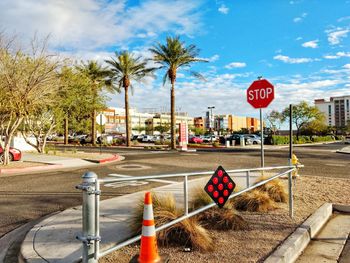 Road sign by palm trees against sky