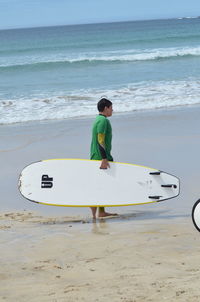 Rear view of man with surfboard on beach