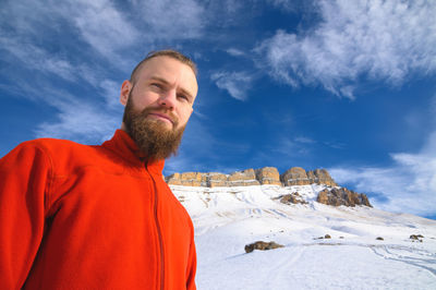 Man looking at snowcapped mountain against sky