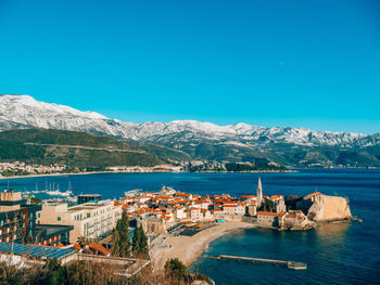 Townscape by sea against clear blue sky