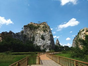 Footbridge leading towards mountains against sky