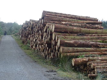 Stack of logs on field against clear sky