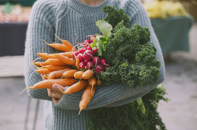 Hands of woman holding fresh vegetables at market