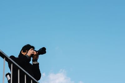 Man photographing against sky on sunny day
