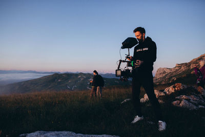 Man photographing on mountain against clear sky