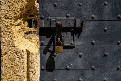 Rusty exterior iron lock on wooden door with metal round buttons.