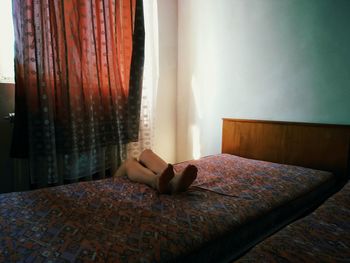 WOMAN SITTING ON BED IN BEDROOM