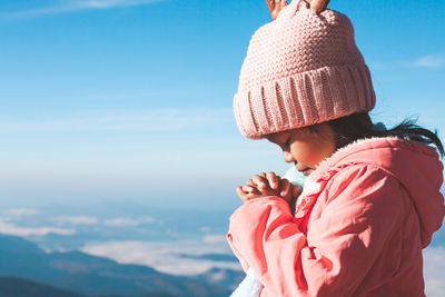 Rear view of mother and daughter against sky during winter