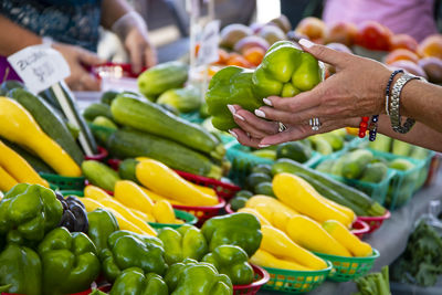 Cropped hands of woman holding bell pepper at vegetables stall in market