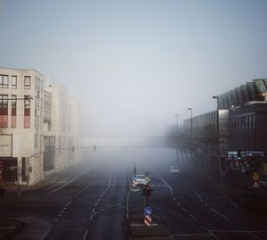 Woman walking on road in city against clear sky