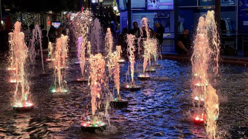 Firework display over fountain in city at night