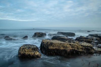 Rocks in sea against sky