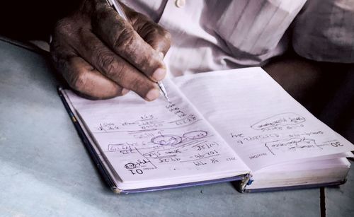 Midsection of man writing on diary