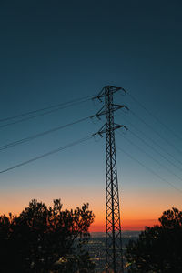 Low angle view of silhouette electricity pylon against sky during sunset