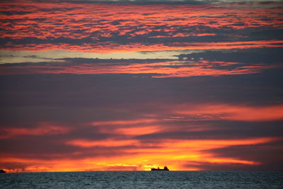 Scenic view of sea against dramatic sky during sunset