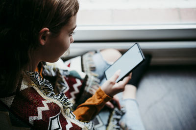 Pre-adolescent girl using mobile phone while sitting at home